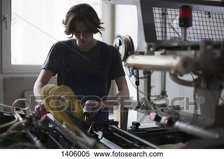 Stock Photography - Young manual worker oiling machine in factory. Fotosearch