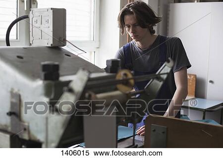 Young manual worker operating machine in factory View Large Photo Image Stock Photography - Young manual worker operating machine in factory. Fotosearch