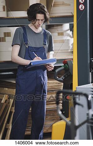 Young manual working writing on paper in a factory View Large Photo Image Picture - Young manual working writing on paper in a factory. Fotosearch