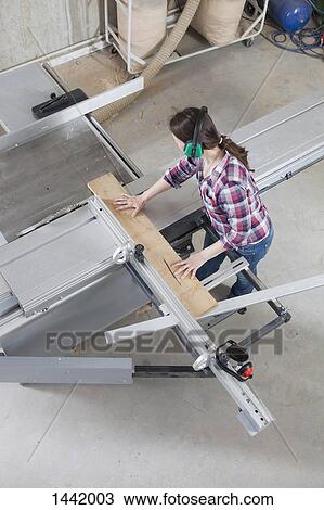 A female carpenter using a sliding table saw in a workshop View Large Photo Image Stock Image - A female carpenter using a sliding table saw in a workshop. Fotosearch