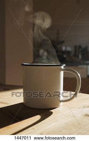 Stock Image - A steaming hot drink in a mug with sunlight, close-up. Fotosearch