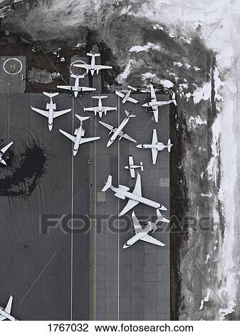 Stock Image - Aerial view private airplanes parked on tarmac surrounded by snow. Fotosearch