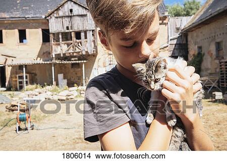 Affectionate boy kissing kitten on sunny farm View Large Photo Image Picture - Affectionate boy kissing kitten on sunny farm. Fotosearch