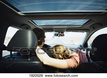 Affectionate couple riding in sunny car View Large Photo Image Stock Photo - Affectionate couple riding in sunny car. Fotosearch