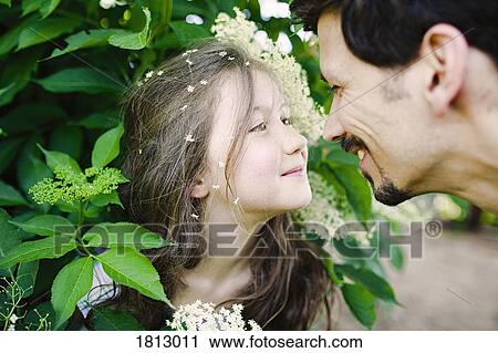 Affectionate father and daughter at flowering bush View Large Photo Image Stock Image - Affectionate father and daughter at flowering bush. Fotosearch
