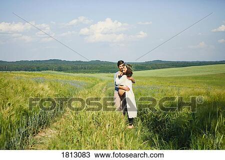 Affectionate pregnant couple hugging in sunny, idyllic rural green field View Large Photo Image Stock Image - Affectionate pregnant couple hugging in sunny, idyllic rural green field. Fotosearch