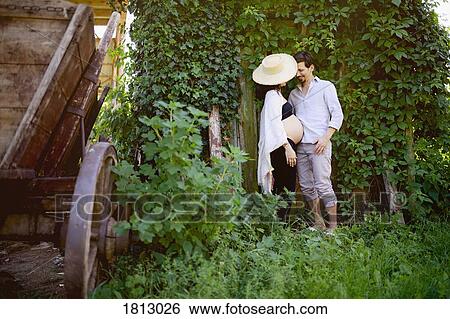 Affectionate pregnant couple standing at ivy covered wall View Large Photo Image Stock Photograph - Affectionate pregnant couple standing at ivy covered wall. Fotosearch