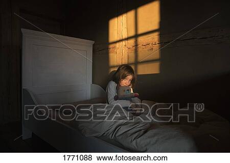 Stock Photo - Afraid girl laying in bed with teddy bear. Fotosearch