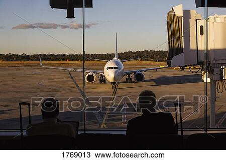 Stock Image - Airplane approaching passenger boarding bridge at airport. Fotosearch