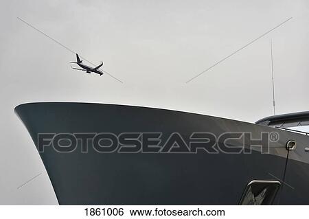 Airplane flying over ship in overcast sky View Large Photo Image Stock Photograph - Airplane flying over ship in overcast sky. Fotosearch