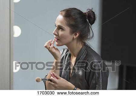 Beautiful woman applying lip balm in front of dressing table View Large Photo Image Stock Image - Beautiful woman applying lip balm in front of dressing table. Fotosearch