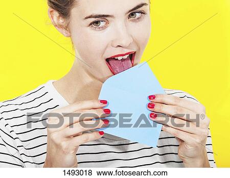 Beautiful woman licking blue envelope against yellow background View Large Photo Image Stock Photo - Beautiful woman licking blue envelope against yellow background. Fotosearch