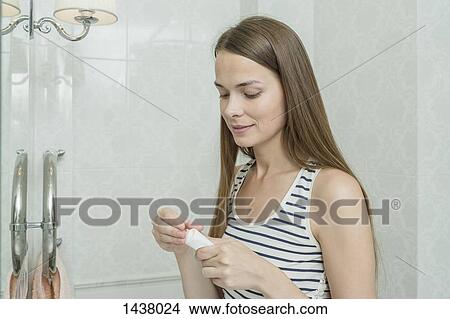 Beautiful woman removing cream from tube in domestic bathroom View Large Photo Image Picture - Beautiful woman removing cream from tube in domestic bathroom. Fotosearch