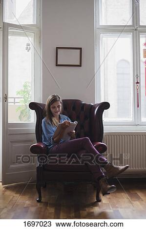 Beautiful young female university student sitting on armchair while reading book at home View Large Photo Image Stock Image - Beautiful young female university student sitting on armchair while reading book at home. Fotosearch