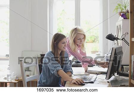 Blond woman pointing at computer monitor to female friend View Large Photo Image Stock Photography - Blond woman pointing at computer monitor to female friend. Fotosearch