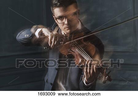 Blurred motion of confident violinist playing violin against wall View Large Photo Image Stock Photo - Blurred motion of confident violinist playing violin against wall. Fotosearch