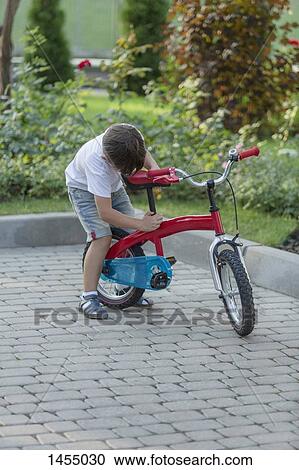 Boy adjusting bicycle seat View Large Photo Image Stock Image - Boy adjusting bicycle seat. Fotosearch