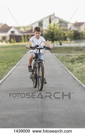 Boy cycling on footpath View Large Photo Image Stock Photo - Boy cycling on footpath. Fotosearch