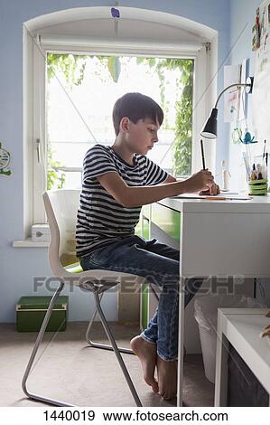 Boy doing homework at table in house View Large Photo Image Stock Photo - Boy doing homework at table in house. Fotosearch