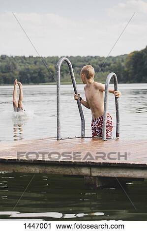 Boy looking at friend sticking out legs out of lake View Large Photo Image Stock Image - Boy looking at friend sticking out legs out of lake. Fotosearch