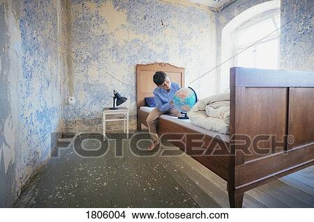 Boy looking at globe on rustic farmhouse bed View Large Photo Image Picture - Boy looking at globe on rustic farmhouse bed. Fotosearch