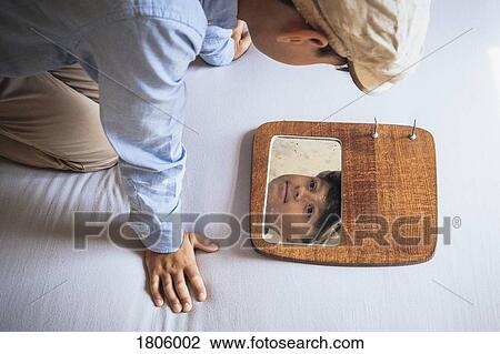 Boy looking at reflection in mirror on bed View Large Photo Image Stock Image - Boy looking at reflection in mirror on bed. Fotosearch