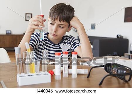 Boy looking at test tube while doing science experiment at home View Large Photo Image Stock Photography - Boy looking at test tube while doing science experiment at home. Fotosearch