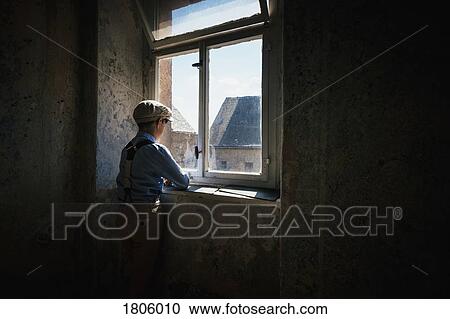 Stock Image - Boy looking out sunny window. Fotosearch