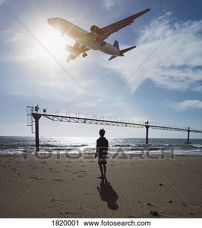 Boy looking up at airplane flying low over ocean near Lanzarote Airport, Puerto del Carmen, Spain View Large Photo Image Stock Image - Boy looking up at airplane flying low over ocean near Lanzarote Airport, Puerto del Carmen, Spain. Fotosearch