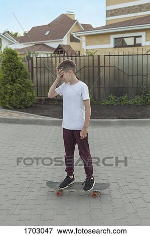 Boy on skateboarding on footpath against houses View Large Photo Image Stock Photo - Boy on skateboarding on footpath against houses. Fotosearch