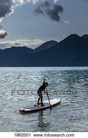 Boy paddleboarding on sunny, idyllic lake, Walchensee, Bavaria, Germany View Large Photo Image Stock Image - Boy paddleboarding on sunny, idyllic lake, Walchensee, Bavaria, Germany. Fotosearch