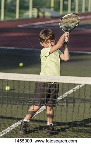 Boy playing tennis in court during sunny day View Large Photo Image Stock Photo - Boy playing tennis in court during sunny day. Fotosearch
