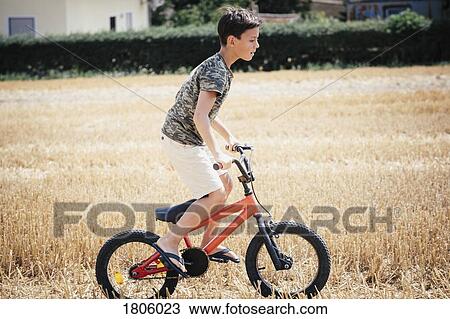Boy riding bicycle in sunny rural field View Large Photo Image Stock Image - Boy riding bicycle in sunny rural field. Fotosearch