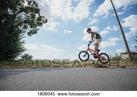 Boy riding bicycle off ramp View Large Photo Image Stock Photography - Boy riding bicycle off ramp. Fotosearch