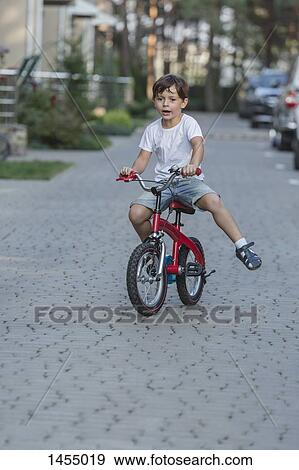Boy riding bicycle on street View Large Photo Image Stock Photo - Boy riding bicycle on street. Fotosearch