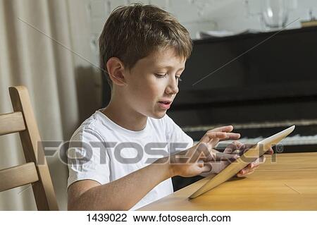 Boy using digital tablet at home View Large Photo Image Stock Image - Boy using digital tablet at home. Fotosearch
