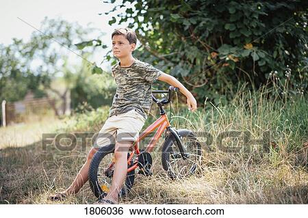 Boy with bicycle in grass View Large Photo Image Stock Photograph - Boy with bicycle in grass. Fotosearch