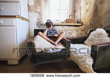Boy with headphones and digital tablet watching video in armchair View Large Photo Image Stock Photo - Boy with headphones and digital tablet watching video in armchair. Fotosearch