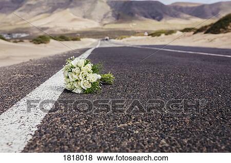 Stock Photo - Bridal bouquet with roses laying on remote road. Fotosearch