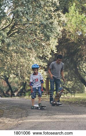 Brothers skateboarding in park View Large Photo Image Stock Photograph - Brothers skateboarding in park. Fotosearch