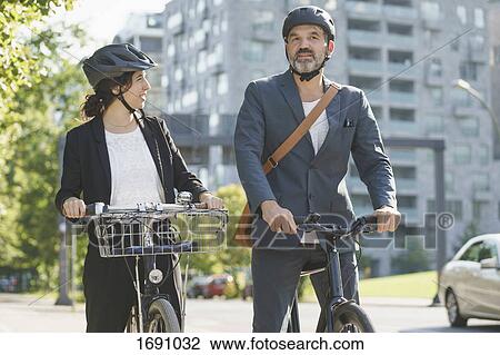Business colleagues talking while riding bicycles in city View Large Photo Image Stock Image - Business colleagues talking while riding bicycles in city. Fotosearch