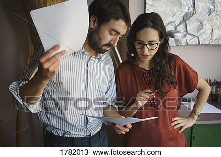 Businessman and businesswoman reviewing paperwork in office View Large Photo Image Stock Image - Businessman and businesswoman reviewing paperwork in office. Fotosearch