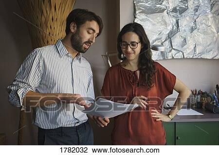 Businessman and businesswoman discussing paperwork in office View Large Photo Image Stock Image - Businessman and businesswoman discussing paperwork in office. Fotosearch