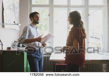 Stock Photograph - Businessman and businesswoman talking in office. Fotosearch