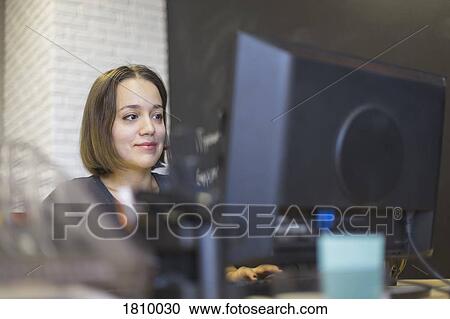 Stock Image - Businesswoman working at computer in office. Fotosearch