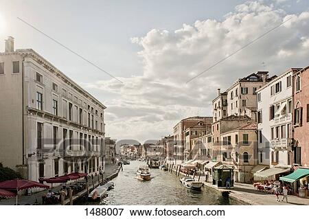 Canal amidst city buildings against sky, Venice, Veneto, Italy View Large Photo Image Stock Photo - Canal amidst city buildings against sky, Venice, Veneto, Italy. Fotosearch