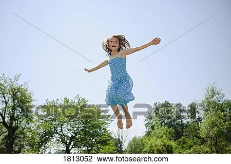Carefree girl in dress jumping for joy in sunny backyard View Large Photo Image Stock Image - Carefree girl in dress jumping for joy in sunny backyard. Fotosearch