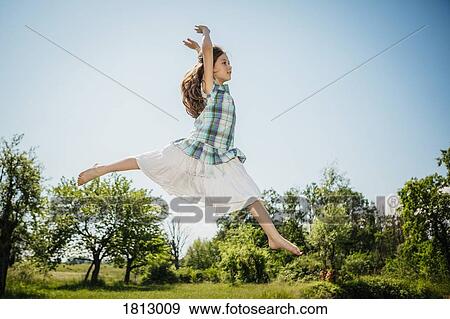 Carefree girl in dress jumping for joy in sunny backyard View Large Photo Image Stock Photo - Carefree girl in dress jumping for joy in sunny backyard. Fotosearch