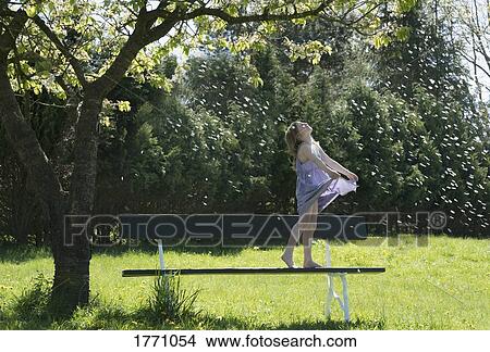 Carefree girl on bench under spring tree with falling spring blossoms View Large Photo Image Picture - Carefree girl on bench under spring tree with falling spring blossoms. Fotosearch