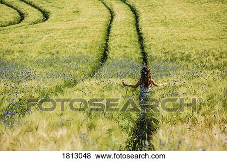 Carefree girl walking in sunny, idyllic rural field with wildflowers View Large Photo Image Stock Photo - Carefree girl walking in sunny, idyllic rural field with wildflowers. Fotosearch